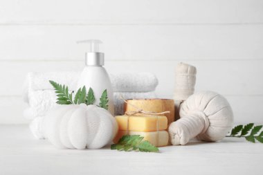 Hafif arkaplanda kaplıca aksesuarları ve bitki yapraklarıyla kompozisyon