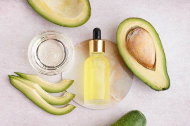 Cam kaseli taze avokadolar ve bej arka planda bir şişe gerekli yağ.