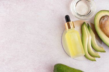 Cam kaseli taze avokado ve bej arka planda bir şişe gerekli yağ.