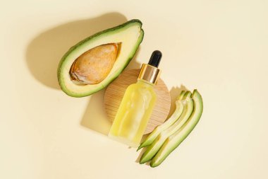Ahşap tezgahlı taze avokado ve bej arka planda bir şişe gerekli yağ.