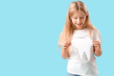 Sağlıklı dişleri ve mavi arka planda kağıt dişleri olan mutlu küçük kız.