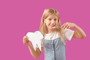 Dişlerini mor arka planda fırçalayan kağıt dişli mutlu küçük kız.