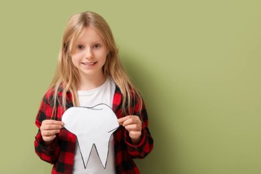 Sağlıklı dişleri ve yeşil arka planda kağıt dişleri olan mutlu küçük kız.