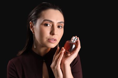 Esmer arka planda parfümü olan güzel bir genç kadın. Yakın plan.