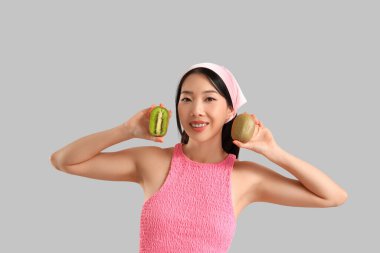 Gri arka planda kivi olan güzel bir Asyalı kadın.