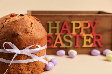 Lezzetli paskalya pastası, boyalı yumurtalar ve bej arka planda ahşap kutu.