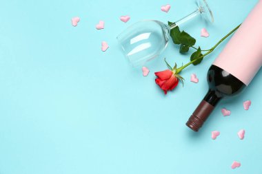 Mavi arka planda Sevgililer Günü için bir şişe şarap ve gül çiçeği kompozisyonu
