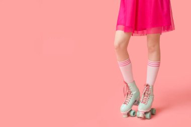 Pembe arka planda eski paten giyen güzel genç bir kadın. Yakın plan.