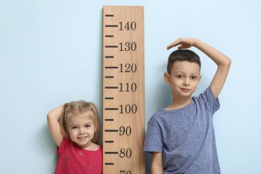 Mavi arka planda boy ölçümü yapan sevimli küçük çocuklar.