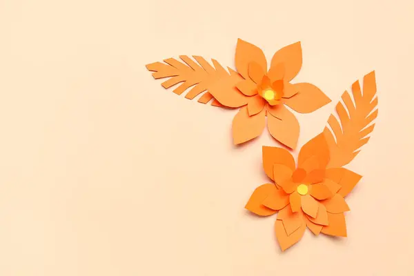 Orange origami flowers and leaves on beige background
