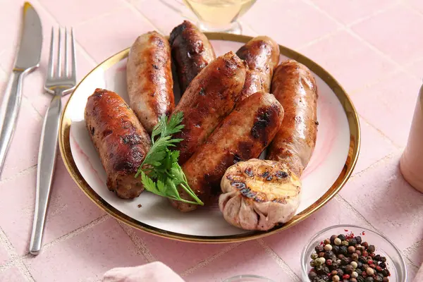 Plate of tasty grilled sausages on pink tile background