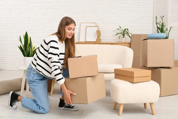 Yeni dairesinde karton kutuları olan güzel genç bir kadın. Taşınma konsepti
