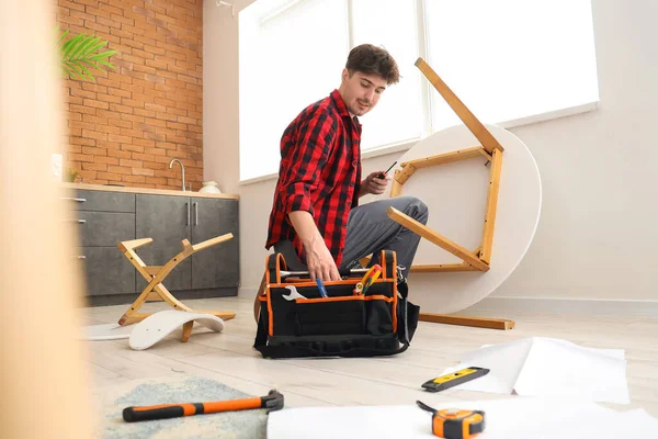 Bir çanta alet edevat taşıyan erkek işçi mutfakta mobilya monte ediyor.