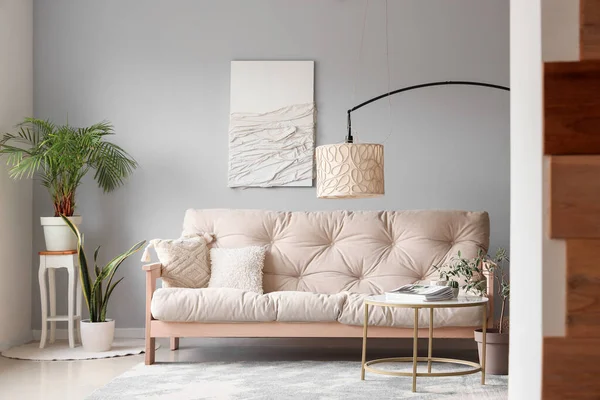 Modern oturma odasının içinde rahat beyaz kanepe, sehpa ve standart lamba var.