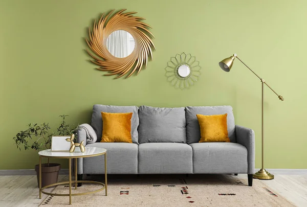 Oturma odasının iç tarafında yastıkları ve kahve masası olan rahat gri bir kanepe.