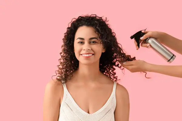 美しいアフリカ系アメリカ人の女性とピンクの背景にヘアスプレー付きの手 — ストック写真