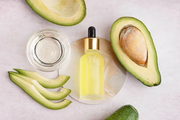 Cam kaseli taze avokadolar ve bej arka planda bir şişe gerekli yağ.