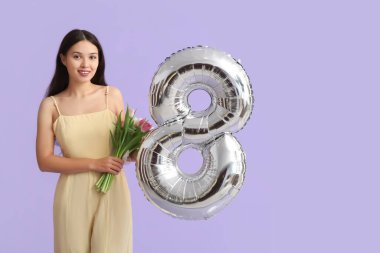 Şekil 8 şeklinde gümüş hava balonu ve mor arka planda güzel laleler olan güzel bir Asyalı kadın. Uluslararası Kadınlar Günü