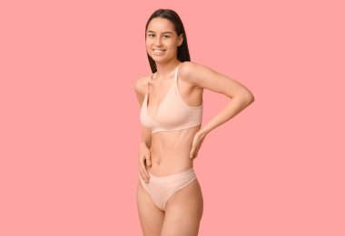 Pembe arka planda iç çamaşırlı güzel bir kadın.