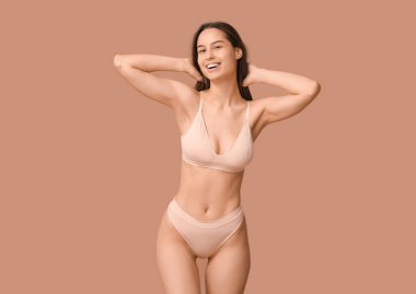 Bej arka planda çıplak iç çamaşırlı güzel bir kadın.