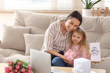 Mutlu genç anne, kızının hediyeleriyle evde görüntülü sohbet ediyor. Anneler Günü kutlaması