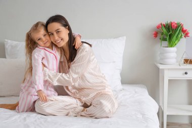 Küçük kız ve mutlu annesi yatak odasında bir buket güzel çiçekle. Anneler Günü kutlaması