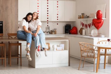 Sevgililer gününde mutfakta oturan genç lezbiyen çift