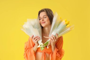 Sarı arka planda lale buketleri olan genç bir kadın. Uluslararası Kadınlar Günü kutlamaları