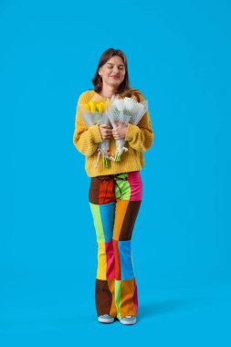 Mavi arka planda lale buketleri olan genç bir kadın. Uluslararası Kadınlar Günü kutlamaları