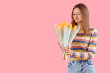 Pembe arka planda sarı lalelerle dolu buketi olan genç bir kadın. Uluslararası Kadınlar Günü kutlamaları