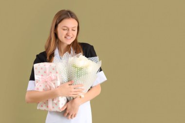 Beyaz lalelerle dolu bir buketi ve yeşil arka planda hediye kutusu olan genç oda hizmetçisi. Uluslararası Kadınlar Günü kutlamaları
