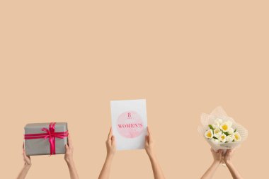 Bir buket lale, hediye kutusu ve bej arka planda bayram kartpostalı olan kadın elleri. Uluslararası Kadınlar Günü kutlamaları
