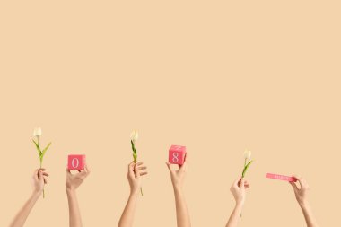 8 Mart tarihli Küp takvimi ve bej arka planda laleleri olan kadın eller. Uluslararası Kadınlar Günü kutlamaları