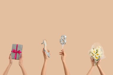 Bir buket lale, yüksek topuklu ayakkabı ve bej arka planda hediye kutusu olan kadın elleri. Uluslararası Kadınlar Günü kutlamaları