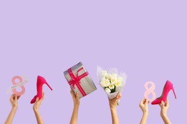 Lale buketli kadın elleri, yüksek topuklu ayakkabılar ve leylak arkaplanlı hediye kutusu. Uluslararası Kadınlar Günü kutlamaları