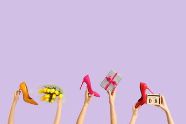Lale desenli kadın elleri, yüksek topuklu ayakkabılar ve leylak arkaplanlı takvim. Uluslararası Kadınlar Günü kutlamaları