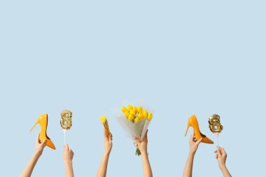 Şekil 8 şeklinde balonları olan kadın elleri, sarı laleler buketi ve mavi arka planda yüksek topuklu ayakkabılar. Uluslararası Kadınlar Günü kutlamaları