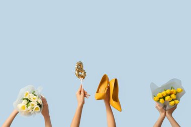 Lale buketli kadın eller, yüksek topuklu ayakkabılar ve mavi arka planda şekil 8 şeklinde balon. Uluslararası Kadınlar Günü kutlamaları