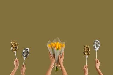 Şekil 8 şeklinde balonları olan kadın eller ve yeşil arka planda sarı laleler. Uluslararası Kadınlar Günü kutlamaları