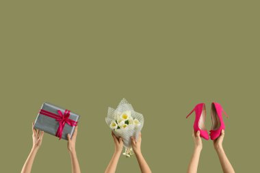 Lale buketi, hediye kutusu ve yeşil arka planda yüksek topuklu ayakkabıları olan kadın elleri. Uluslararası Kadınlar Günü kutlamaları