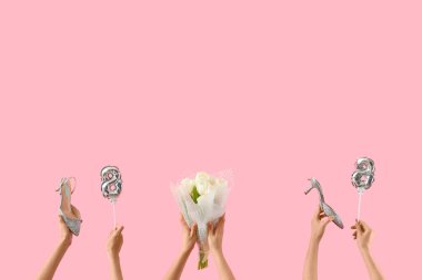 Şekil 8 şeklinde balonları olan kadın eller, pembe arka planda bir buket lale ve yüksek topuklu ayakkabılar. Uluslararası Kadınlar Günü kutlamaları
