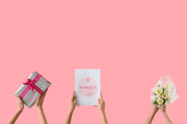 Lale buketi, hediye kutusu ve pembe arka planda bayram kartpostalı olan kadın elleri. Uluslararası Kadınlar Günü kutlamaları