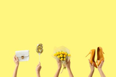 Lale buketli kadın elleri, yüksek topuklu ayakkabılar ve sarı arka planda el çantası. Uluslararası Kadınlar Günü kutlamaları