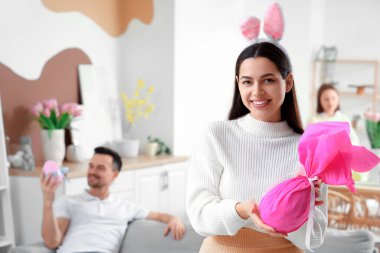 Paskalya günü evde hediye yumurtasıyla tavşan kulaklı mutlu anne.