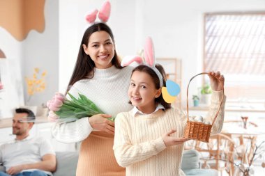 Paskalya Günü 'nde elinde yumurta sepeti ve annesi olan küçük bir kız.