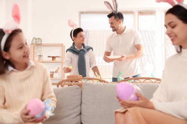 Paskalya günü babasıyla birlikte evde yemek masasını dekore eden küçük bir çocuk.