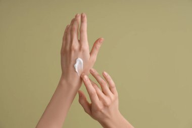 Yeşil arka planda krem süren kadın, yakın plan.