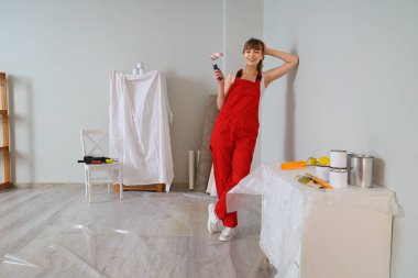 Boya silindirli kadın dekoratör odada tamirat yapıyor.