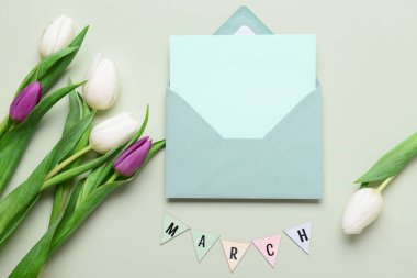 Boş kartlı zarf ve gri arka planda lale çiçekleri. Uluslararası Kadınlar Günü kutlamaları