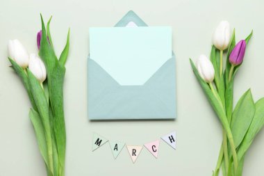 Boş kartlı zarf ve gri arka planda lale çiçekleri. Uluslararası Kadınlar Günü kutlamaları